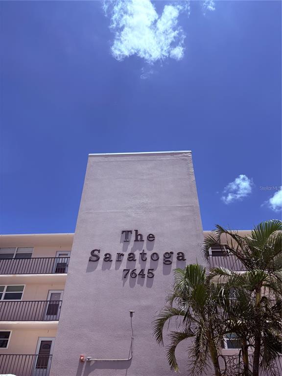 A low-angle view of a multi-story apartment building exterior with a palm tree — 7645 SUN ISLAND DRIVE S UNIT 101, SOUTH PASADENA, FL