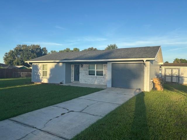 A single-story house with a gray exterior, a front-facing garage, and a concrete driveway — 13233 GRAND TERRACE DRIVE, GRAND ISLAND, FL