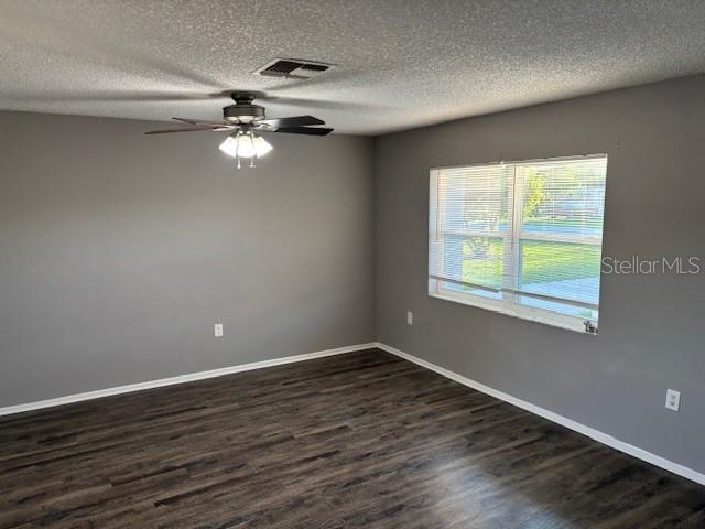 An empty room with gray walls, a ceiling fan, and dark wood-look flooring — 13233 GRAND TERRACE DRIVE, GRAND ISLAND, FL