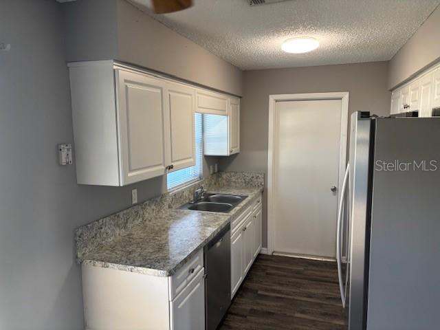 A kitchen features white cabinets, granite-look countertops, stainless steel appliances, and wood-look flooring — 13233 GRAND TERRACE DRIVE, GRAND ISLAND, FL