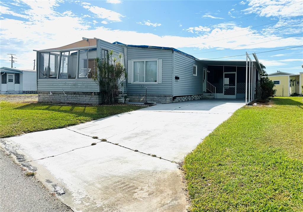 A light blue manufactured home with a concrete driveway, a sunroom, and a carport — 361 TAMPICO DRIVE, PALMETTO, FL