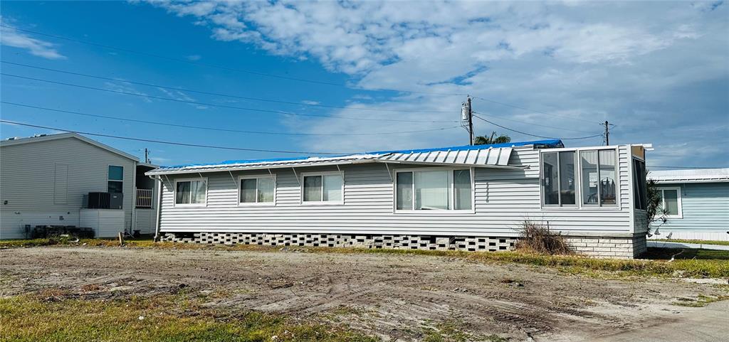 A single-story manufactured home with a blue tarp covering part of its damaged roof — 361 TAMPICO DRIVE, PALMETTO, FL