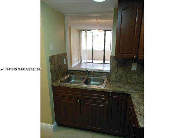 A kitchen sink with a pass-through window overlooking a living area with a balcony — 8335 SW 152 AV # 308, Miami FL 33193, MIAMI, FL