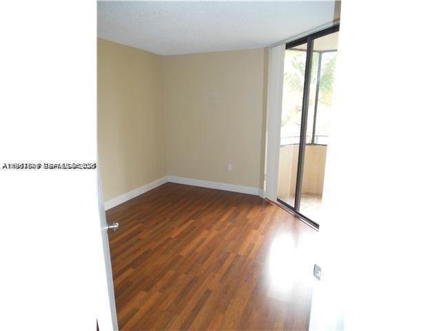 An empty room with wood-look flooring and a sliding glass door leading to a balcony — 8335 SW 152 AV # 308, Miami FL 33193, MIAMI, FL
