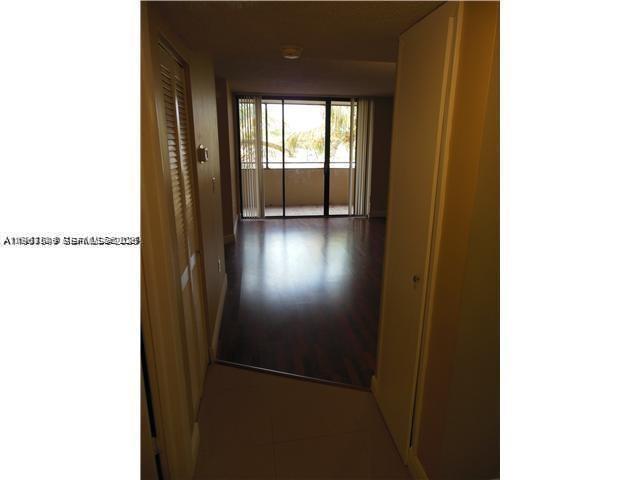 An interior view shows a hallway with tile flooring leading to a living area with wood floors — 8335 SW 152 AV # 308, Miami FL 33193, MIAMI, FL