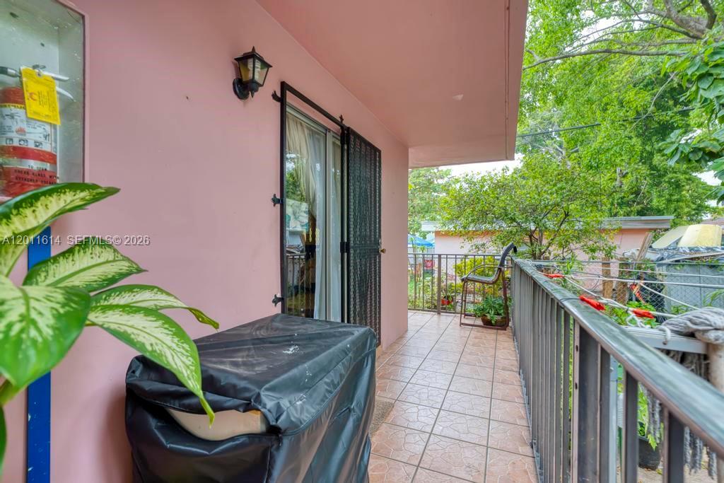 A covered balcony with tiled flooring, a metal railing, and a sliding glass door entrance — 519 NW 10th Ave, Miami FL 33136, MIAMI, FL