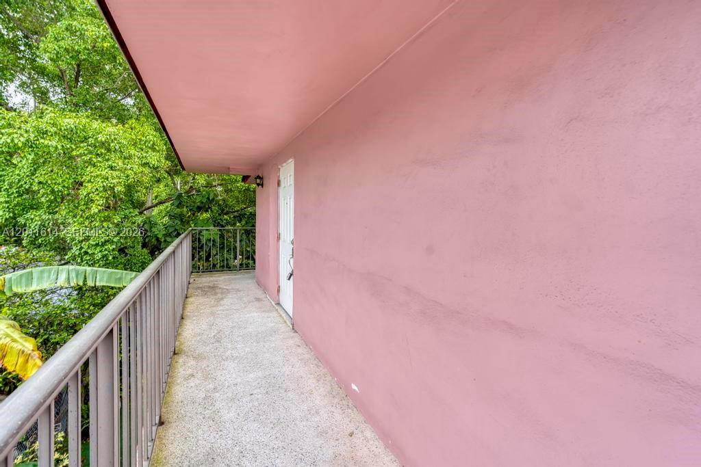 An exterior walkway with a metal railing runs alongside a pink building wall — 519 NW 10th Ave, Miami FL 33136, MIAMI, FL