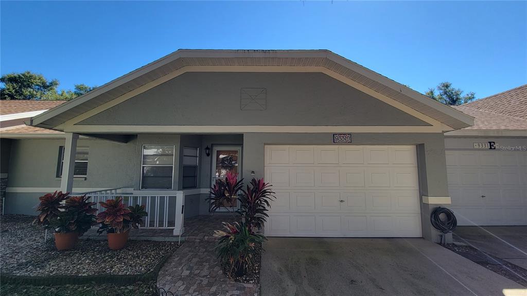The exterior of a single-story house features a garage, a front porch, and landscaping — 9331 SW 84TH TERRACE UNIT D, OCALA, FL