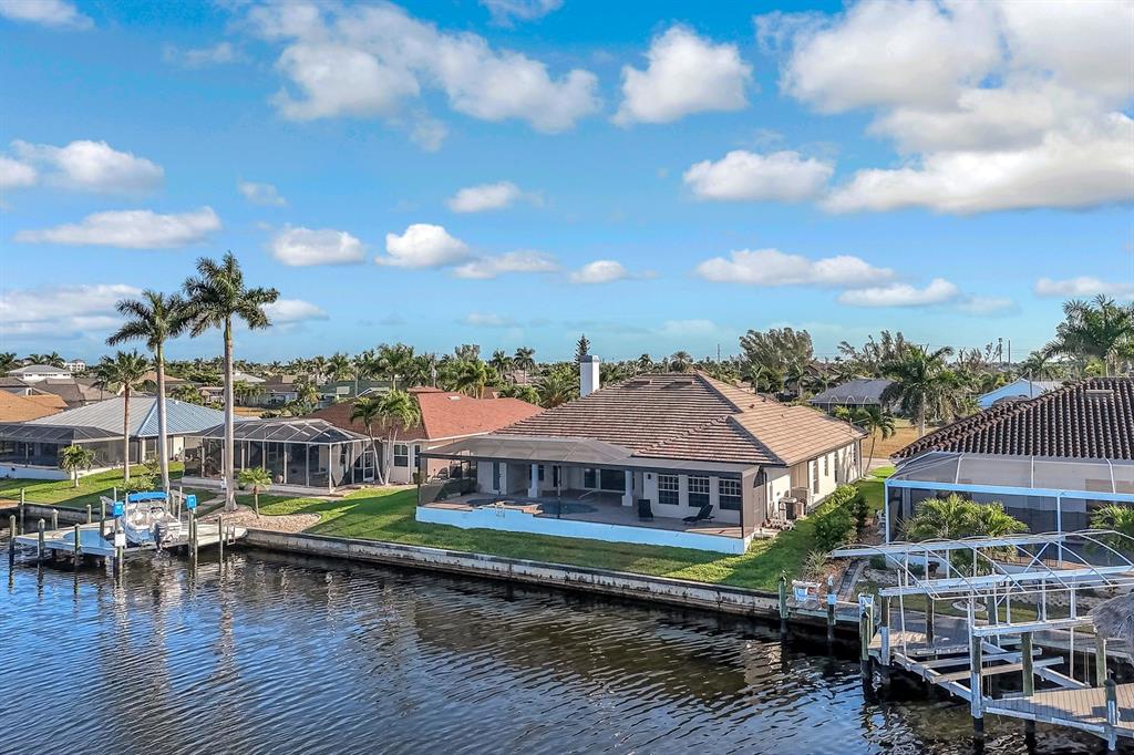 An aerial view shows a waterfront house with a screened-in pool and a private dock — 4518 SW 22ND PLACE, CAPE CORAL, FL
