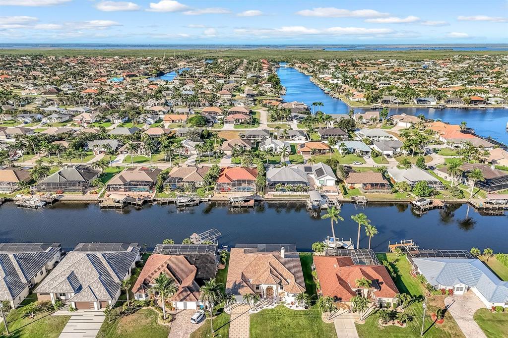 An aerial view shows waterfront homes with swimming pools and private docks along a canal — 4518 SW 22ND PLACE, CAPE CORAL, FL