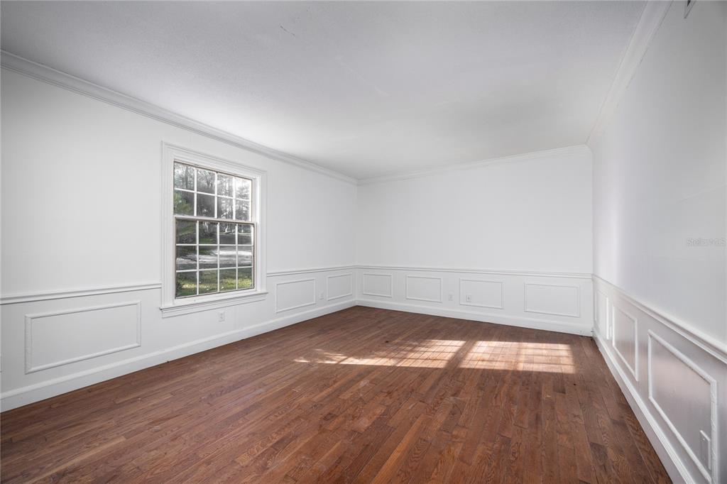 An empty room with white walls, wainscoting, and dark hardwood flooring features a single window — 1701 NW 30TH TERRACE, GAINESVILLE, FL