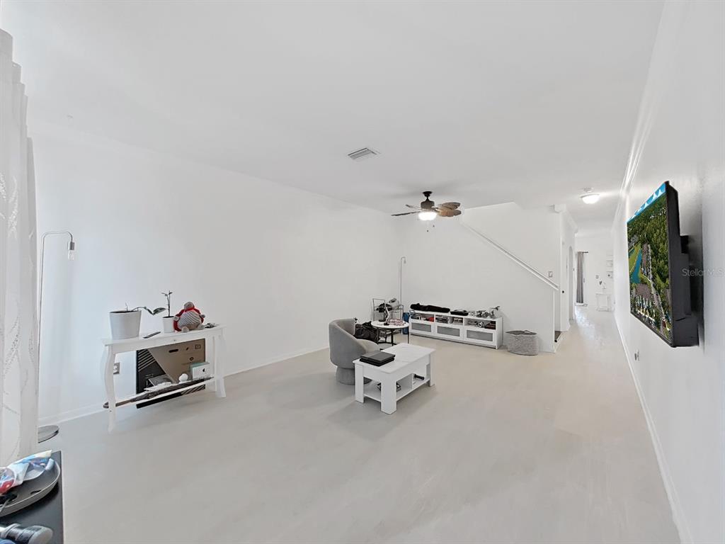 A living room with white walls, light flooring, a ceiling fan, and a wall-mounted television — 18126 PARADISE POINT DRIVE, TAMPA, FL