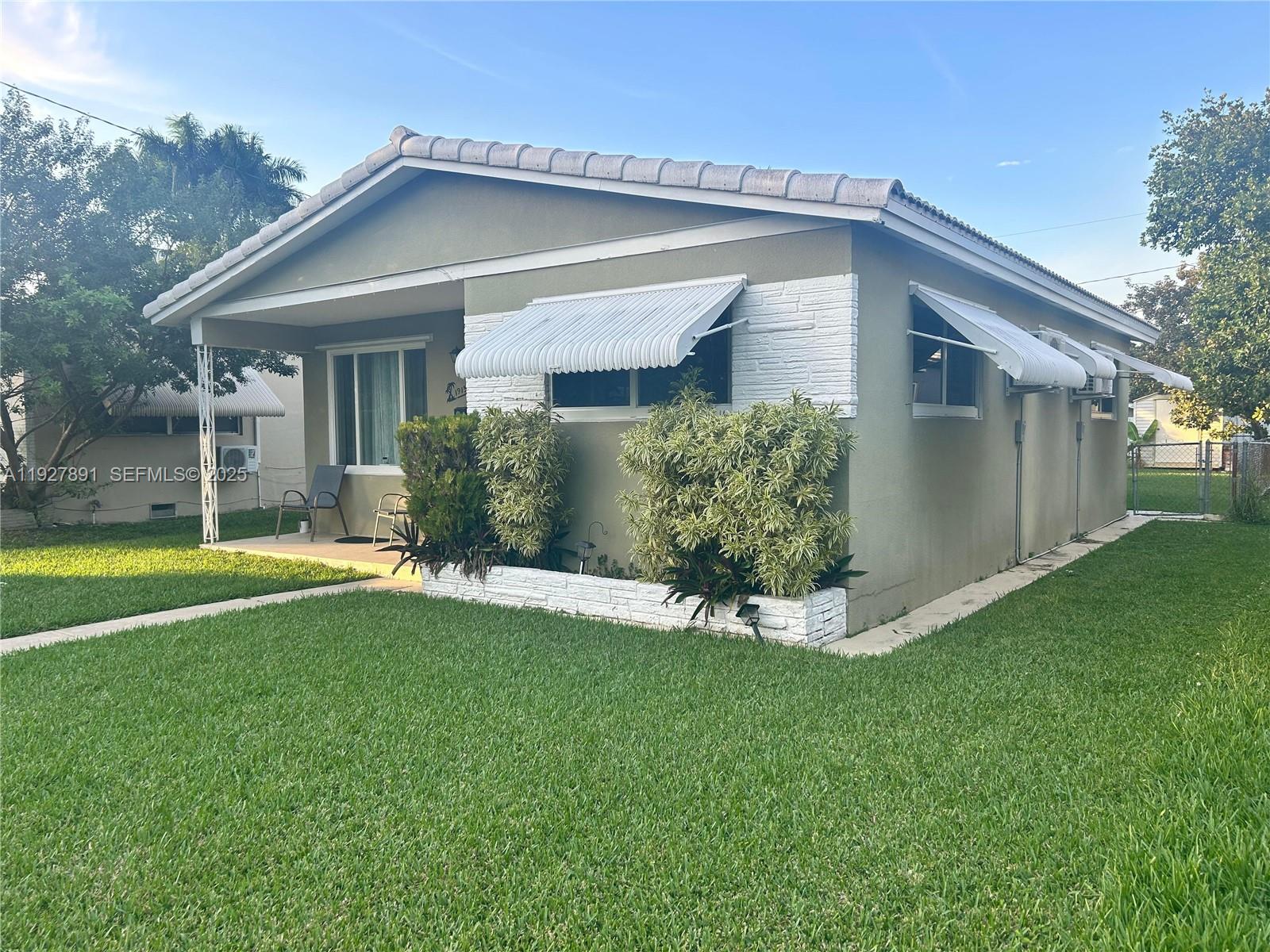 A single-story house with a covered front porch, white door, and a green lawn — 1915 Mayo St, Hollywood FL 33020, HOLLYWOOD, FL