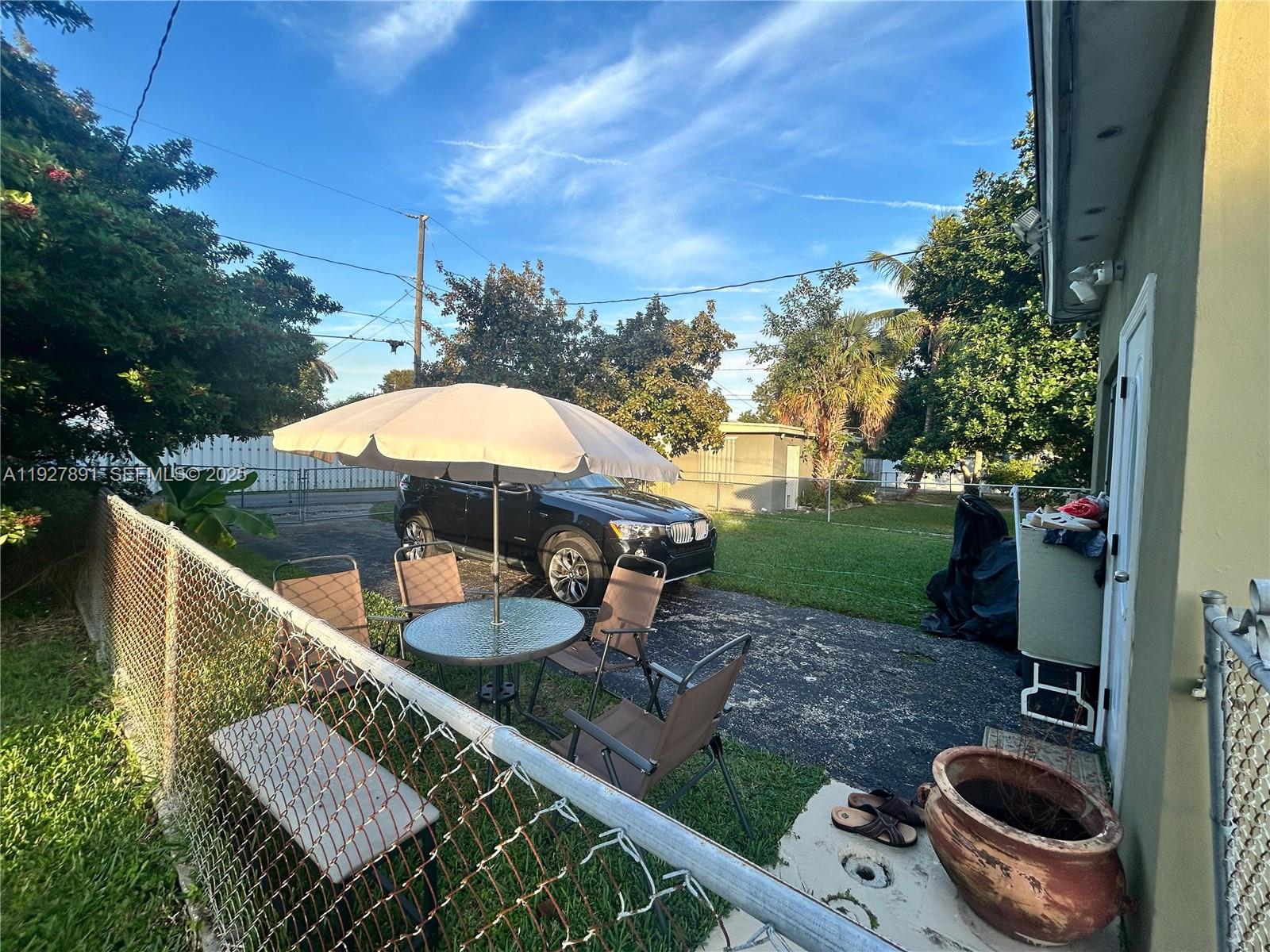 The exterior side of a house features stucco walls, white awnings, and window air conditioners — 1915 Mayo St, Hollywood FL 33020, HOLLYWOOD, FL