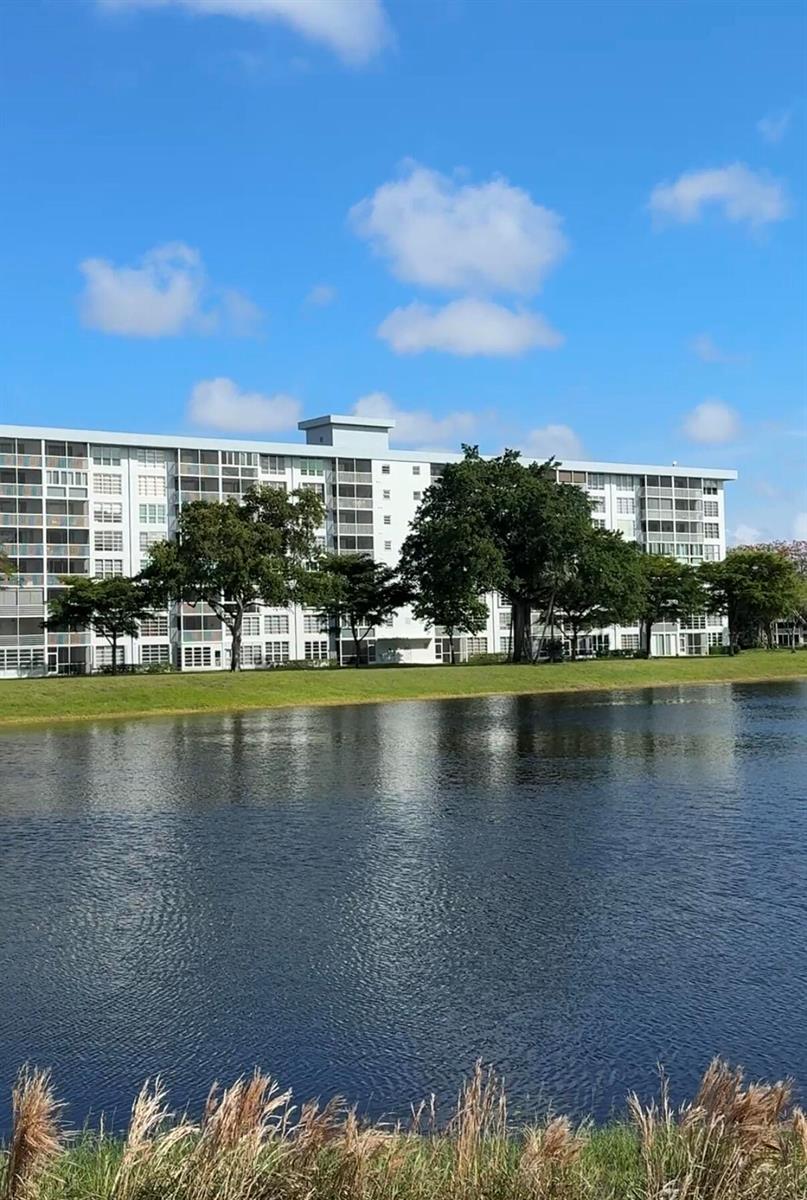 A kitchen features wood cabinets, a dark granite countertop, and a decorative bowl on the island — 3080 N Course Drive # 202, Pompano Beach FL 33069, POMPANO BEACH, FL