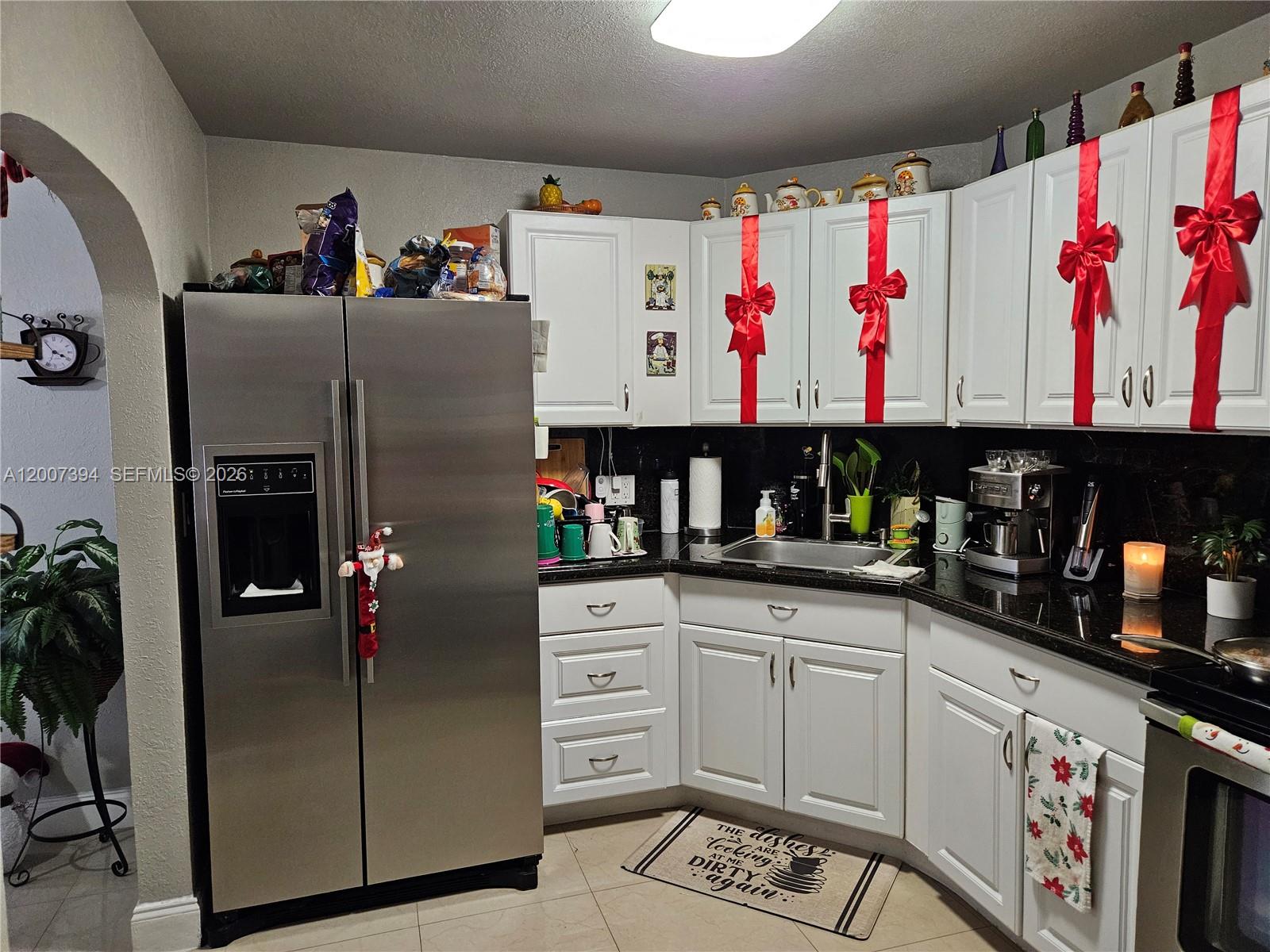 A kitchen features white cabinets decorated with red bows, stainless steel appliances, and dark countertops — 3431-3433 SW 4th St, Miami FL 33135, MIAMI, FL