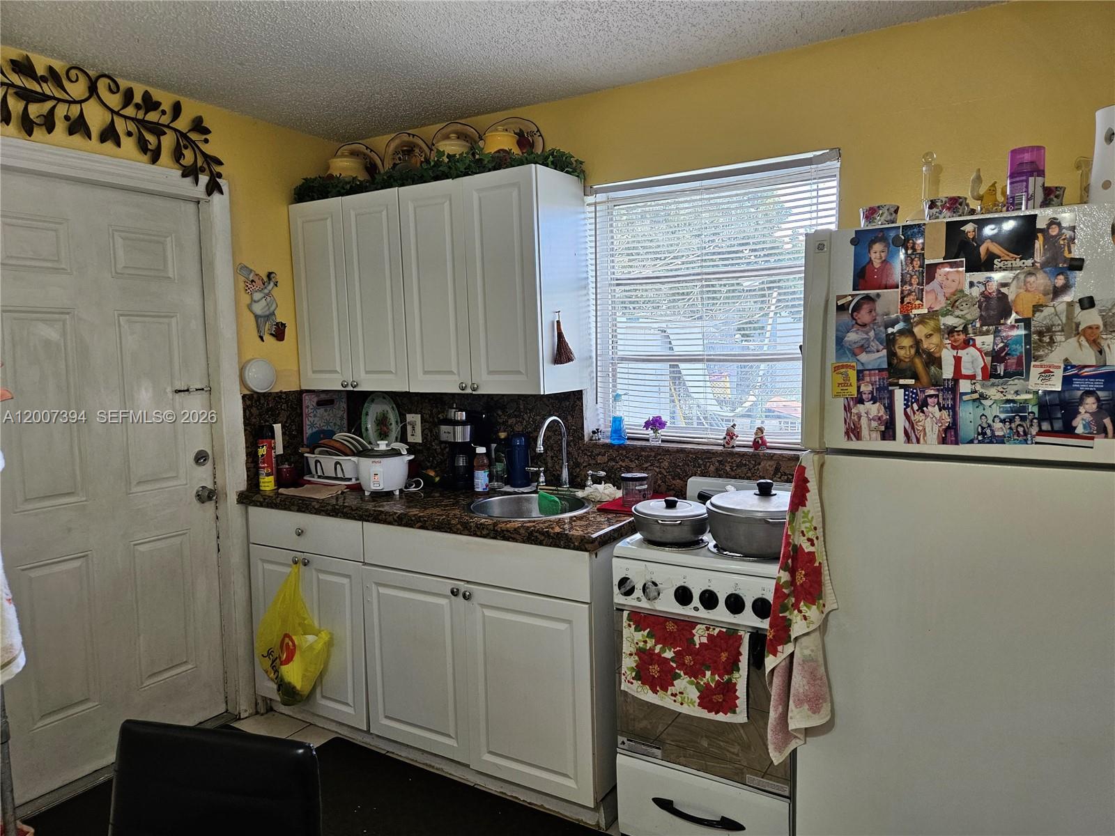 A kitchen features white cabinets, granite countertops, a stove, and a refrigerator with photos — 3431-3433 SW 4th St, Miami FL 33135, MIAMI, FL