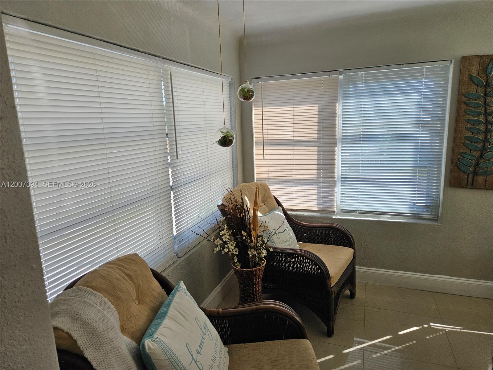 A sunroom features two wicker chairs, hanging glass planters, and windows with white blinds — 3431-3433 SW 4th St, Miami FL 33135, MIAMI, FL