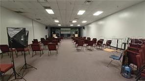 A large, carpeted meeting room features rows of chairs, a stage, and overhead fluorescent lighting — 2921 S ORLANDO DRIVE UNIT 178, SANFORD, FL