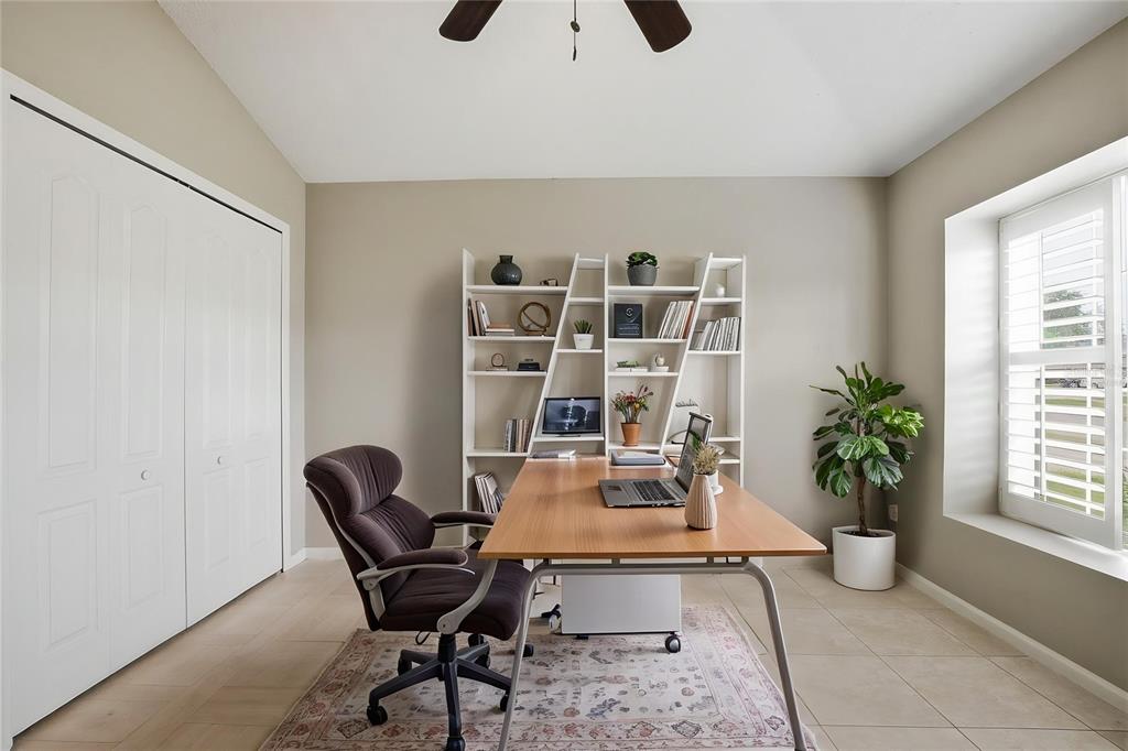 A home office features a wooden desk, an ergonomic chair, a bookshelf, and tile flooring — 15833 BAY VISTA DRIVE, CLERMONT, FL
