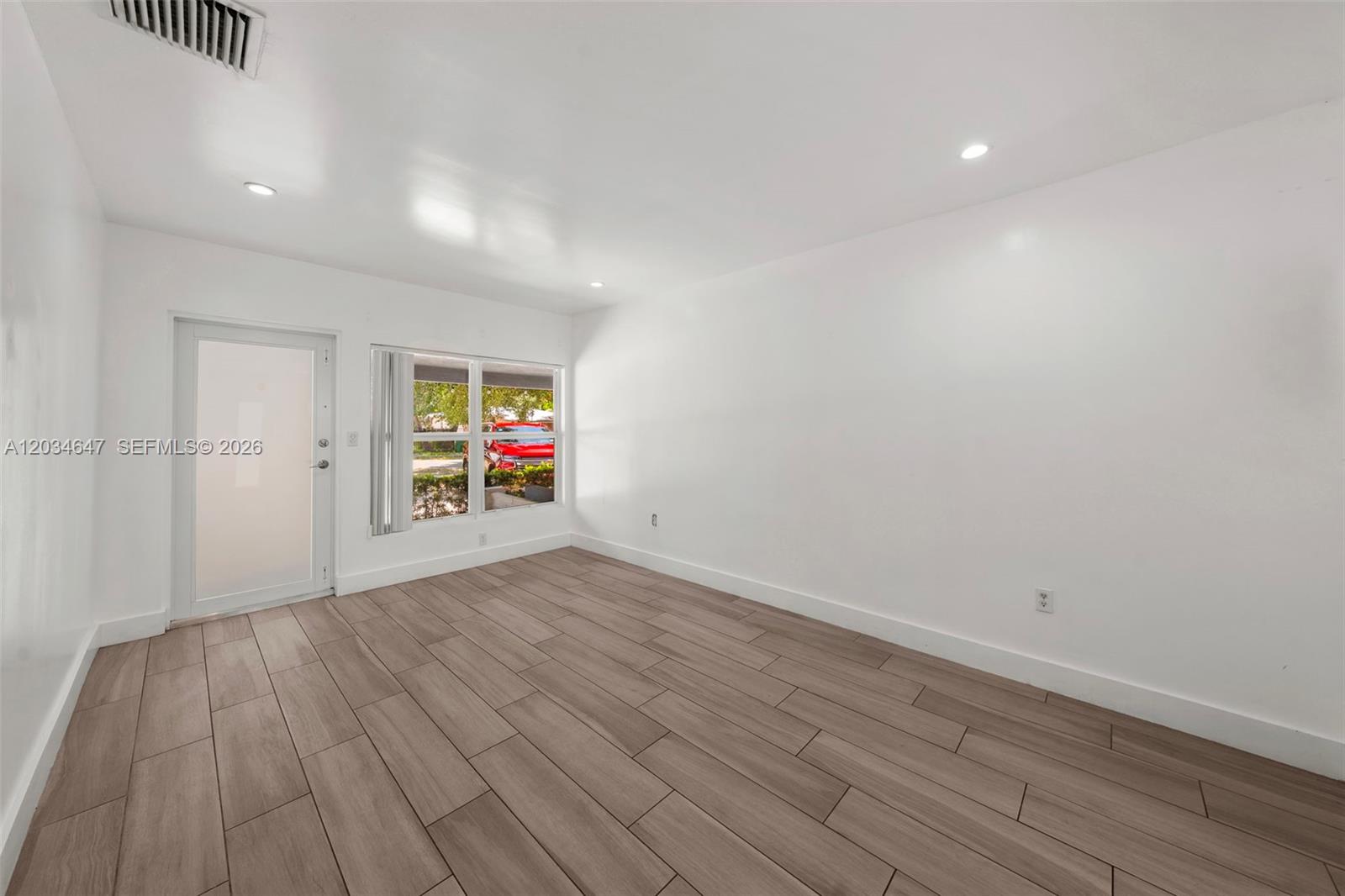 An empty room features white walls, recessed lighting, and light-colored wood-look tile flooring — 520 NW 104th St # 520, Miami FL 33150, MIAMI, FL