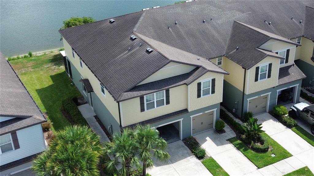 An aerial view of a multi-story townhouse complex with garages and a nearby lake — 9154 HILLCROFT DRIVE, RIVERVIEW, FL