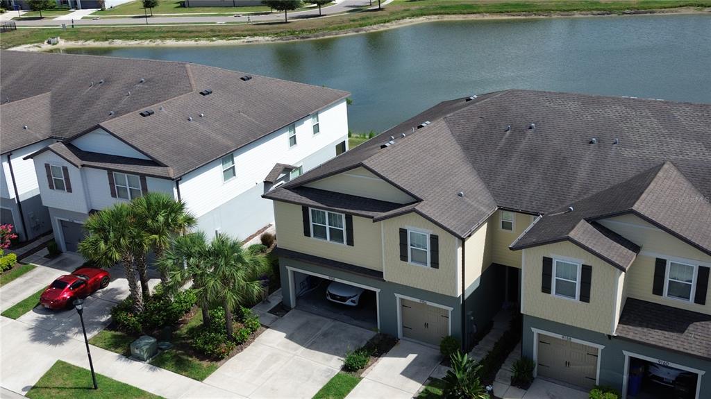 An aerial view shows two multi-story townhouses with attached garages situated beside a pond — 9154 HILLCROFT DRIVE, RIVERVIEW, FL