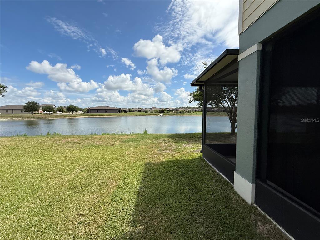 A view of a backyard lawn and a pond from a screened-in patio — 9154 HILLCROFT DRIVE, RIVERVIEW, FL