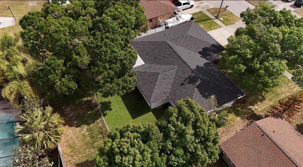 An aerial view of a house with a dark shingled roof surrounded by mature trees — 6111 18TH STREET, ZEPHYRHILLS, FL