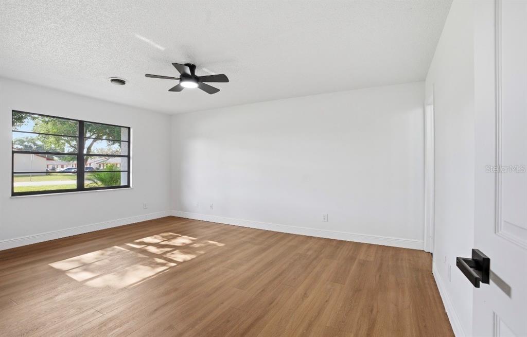 An empty bedroom features white walls, light wood-look flooring, and a ceiling fan — 6111 18TH STREET, ZEPHYRHILLS, FL