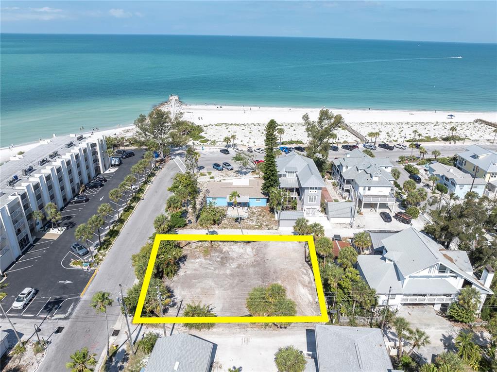 An aerial view shows a vacant rectangular lot near a beach and coastal buildings — 103 & 105 1ST AVENUE, ST PETE BEACH, FL