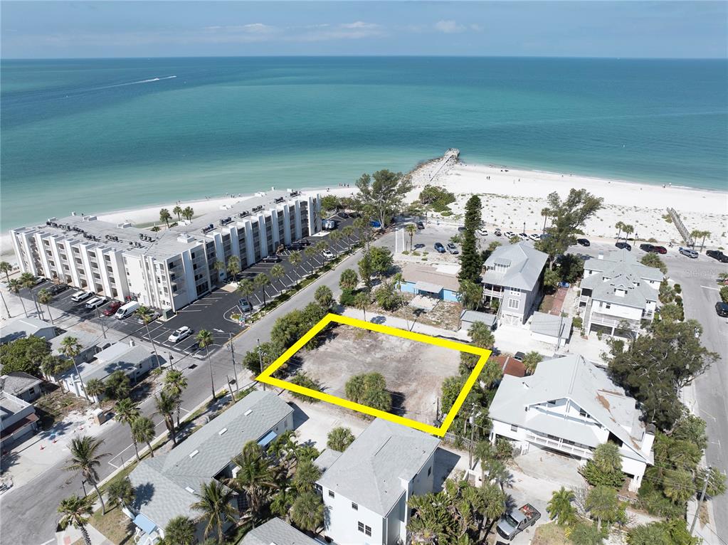 An aerial view shows a vacant, rectangular lot highlighted in yellow near a beach — 103 & 105 1ST AVENUE, ST PETE BEACH, FL