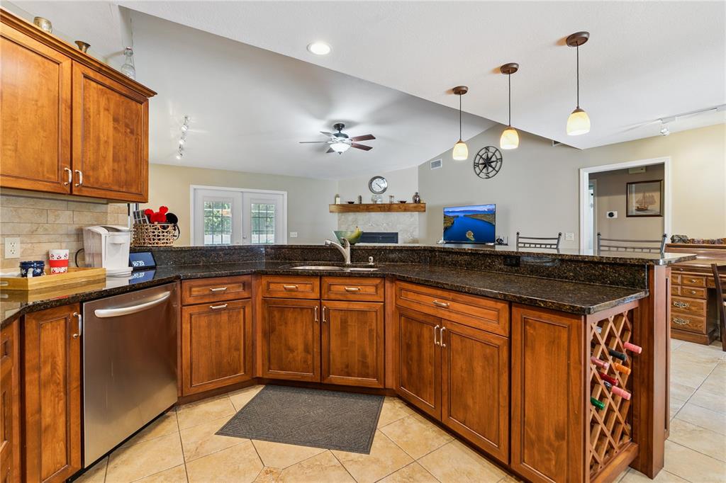 A kitchen features wood cabinets, dark granite countertops, stainless steel appliances, and a wine rack — 7050 SCENIC HILLS BOULEVARD, LAKELAND, FL