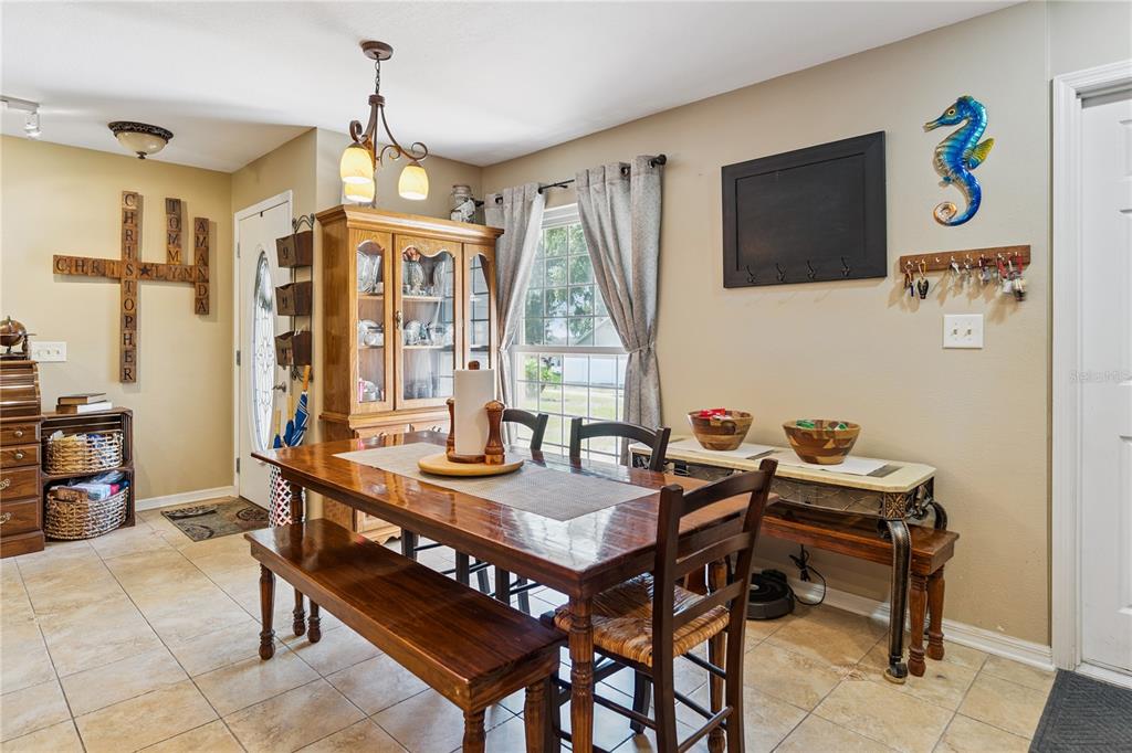 A dining room features a wooden table with a bench, a hutch, and tile flooring — 7050 SCENIC HILLS BOULEVARD, LAKELAND, FL