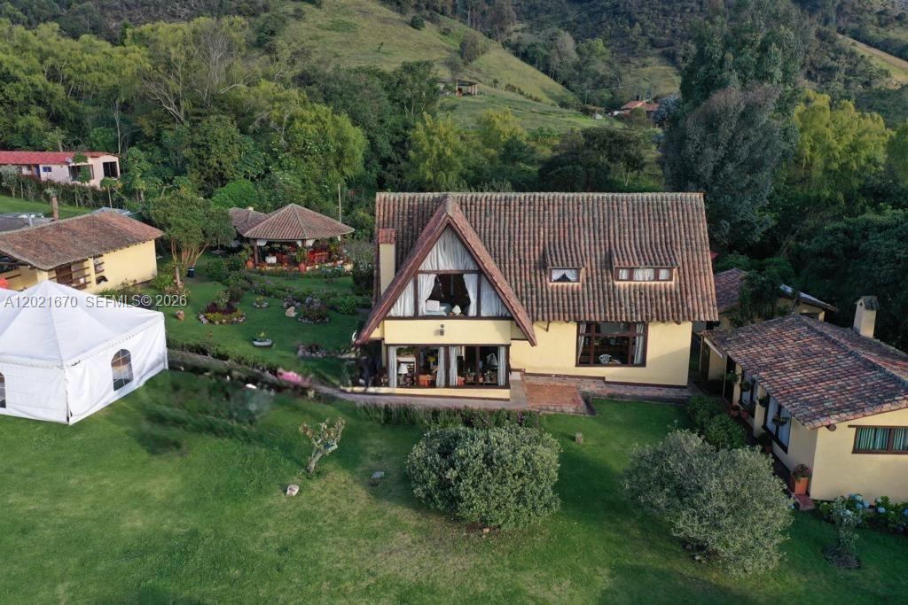 An aerial view shows a house with a tiled roof and surrounding green lawns — Subachoque Cundinamarca Colombia, 250220, FL