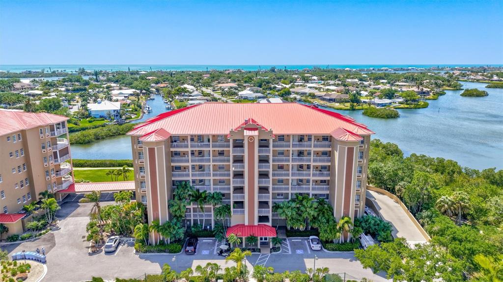 An aerial view shows a multi-story apartment building with a red metal roof — 5100 JESSIE HARBOR DRIVE UNIT 304, OSPREY, FL