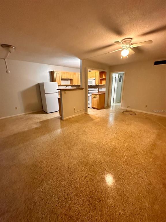 An open-concept living area features terrazzo flooring, a kitchen with light wood cabinets, and a ceiling fan — 305 E DAKIN AVENUE UNIT 11, KISSIMMEE, FL