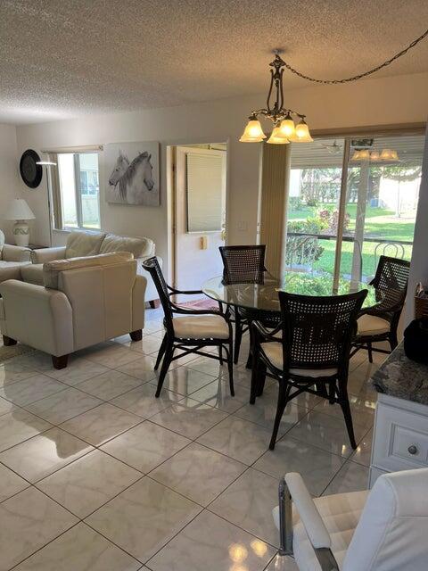 A living and dining area features tiled floors, a glass-topped table, and sliding glass doors — 311 Pine Ridge Circle # 1, FL 33463, FL