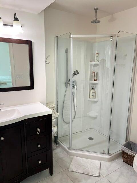 A bathroom features a dark wood vanity, a wall mirror, and a corner glass shower stall — 311 Pine Ridge Circle # 1, FL 33463, FL