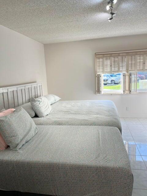 A bedroom features two beds, a white shutter-style headboard, and a window with plantation shutters — 311 Pine Ridge Circle # 1, FL 33463, FL
