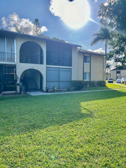 A two-story apartment building features arched entryways, screened balconies, and a grassy lawn — 311 Pine Ridge Circle # 1, FL 33463, FL