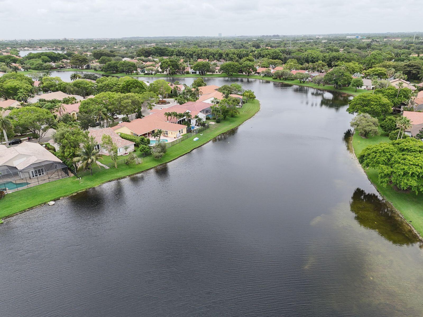 An aerial view shows houses with tile roofs along a lake in a residential neighborhood — 1968 Water Ridge Drive, Weston FL 33326, WESTON, FL