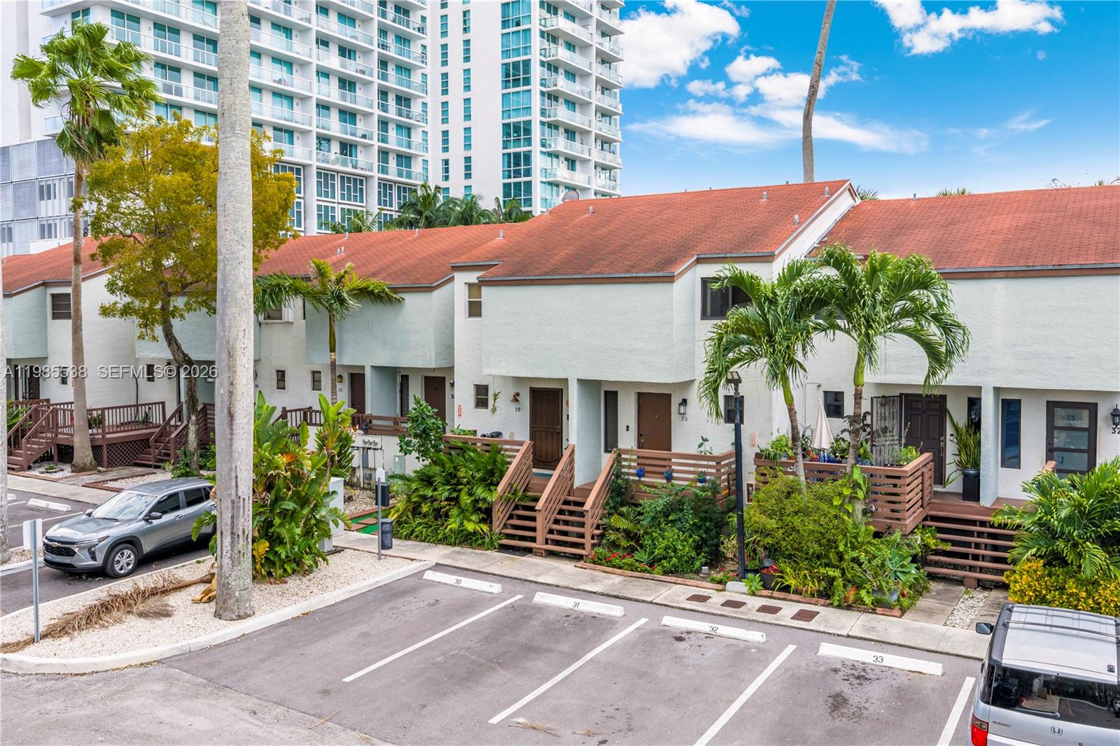 An exterior view of a multi-unit townhouse complex with parking spaces in the foreground — 1901 NW S River Dr # 30C, Miami FL 33125, MIAMI, FL