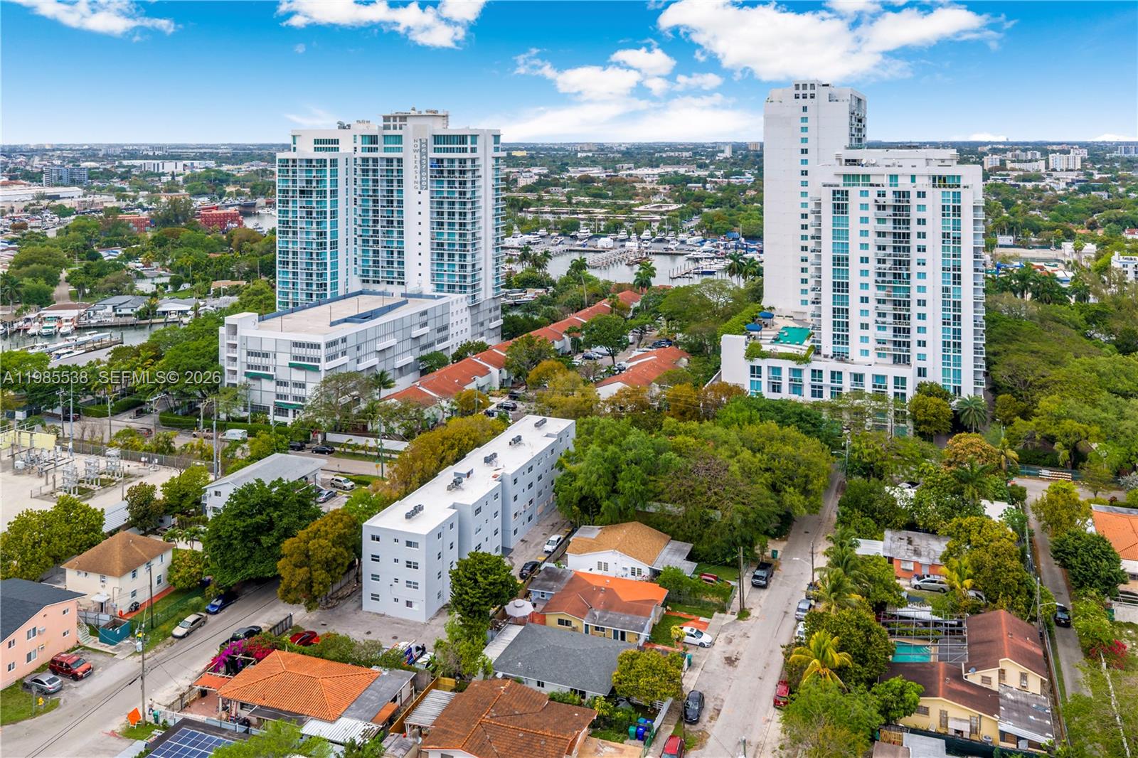 An aerial view shows residential buildings, a marina, and dense trees under a cloudy sky — 1901 NW S River Dr # 30C, Miami FL 33125, MIAMI, FL