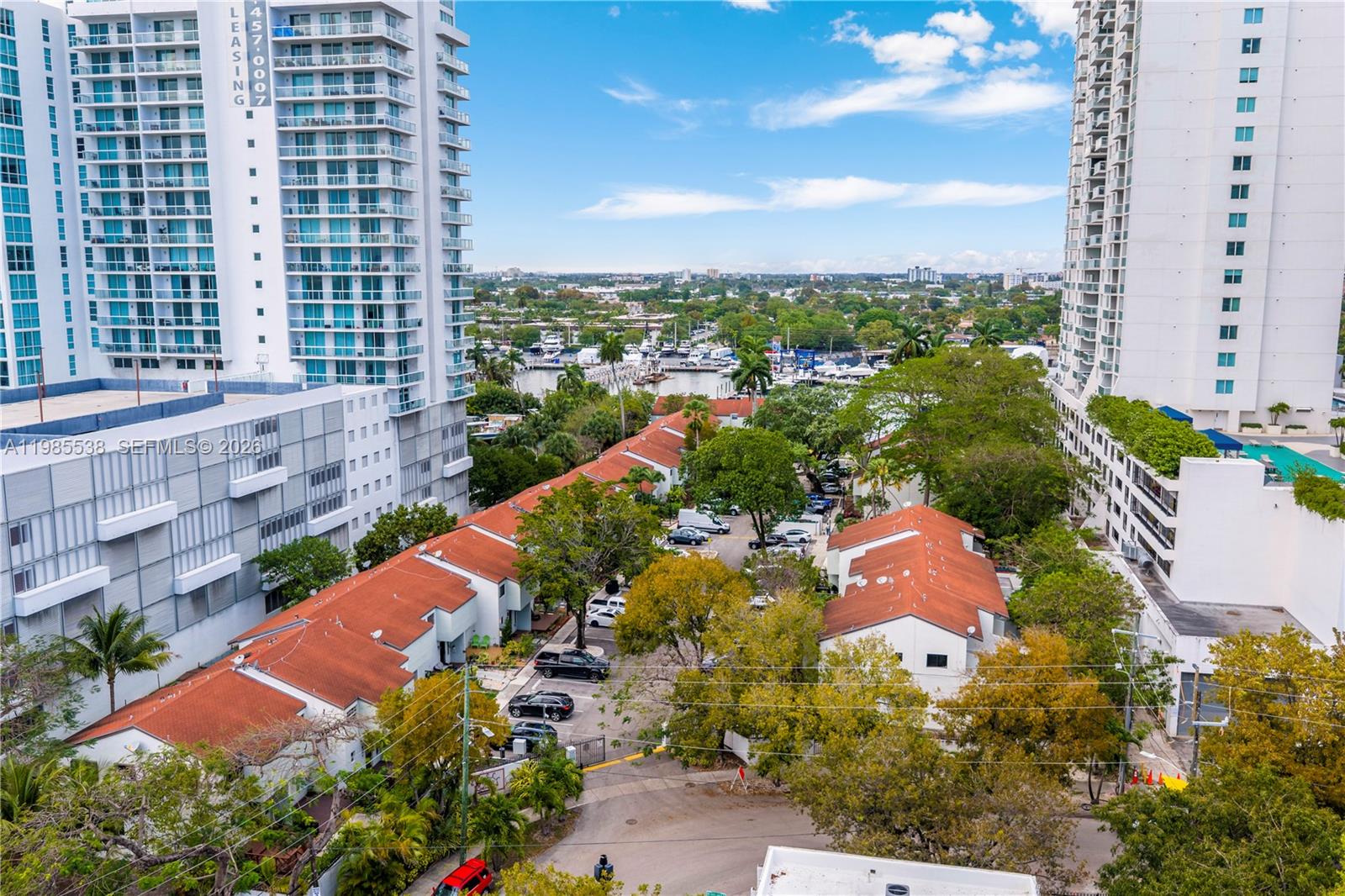 An aerial view shows low-rise residential buildings with red roofs nestled between two high-rise towers — 1901 NW S River Dr # 30C, Miami FL 33125, MIAMI, FL