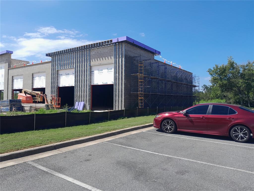 A red car is parked in front of a commercial building under construction — 11697 PANAMA CITY BEACH PARKWAY, PANAMA CITY BEACH, FL