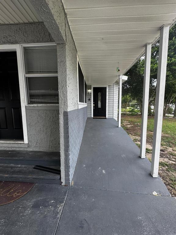 A covered concrete porch leads to a black front door on a gray house exterior — 435 16TH STREET NE, WINTER HAVEN, FL