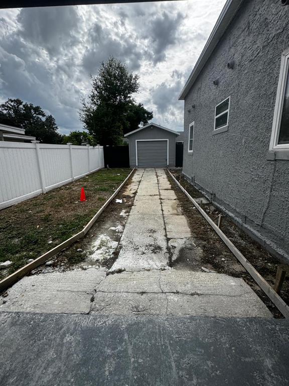 A narrow concrete driveway leads toward a detached garage beside a gray stucco house — 435 16TH STREET NE, WINTER HAVEN, FL