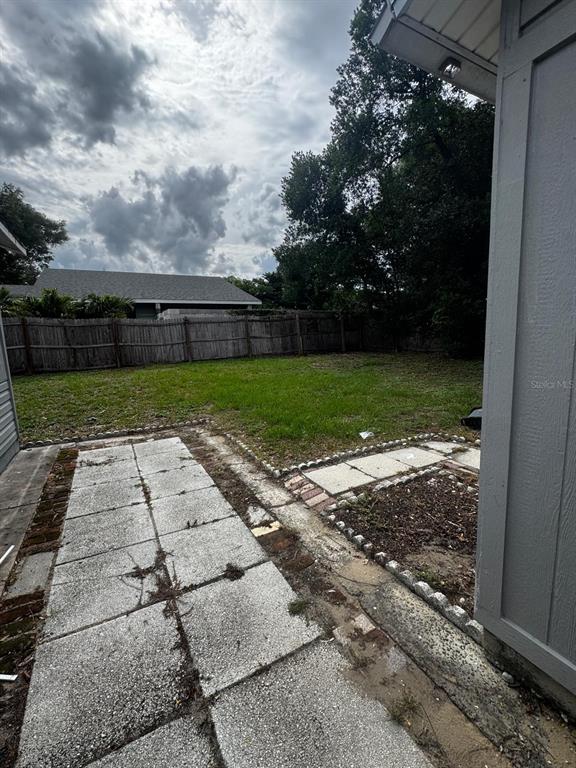 A backyard features a concrete paver patio, a wooden fence, and a grassy lawn — 435 16TH STREET NE, WINTER HAVEN, FL