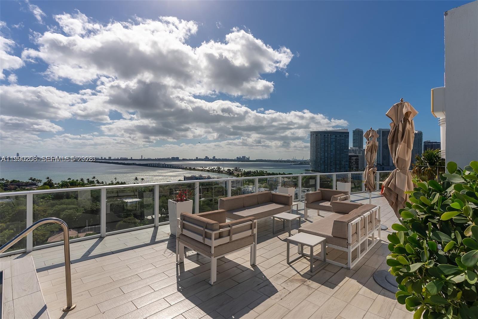 A rooftop terrace features outdoor seating, a glass railing, and a panoramic view of the bay — 4250 NE Biscayne Blvd # 1115, Miami FL 33137, MIAMI, FL